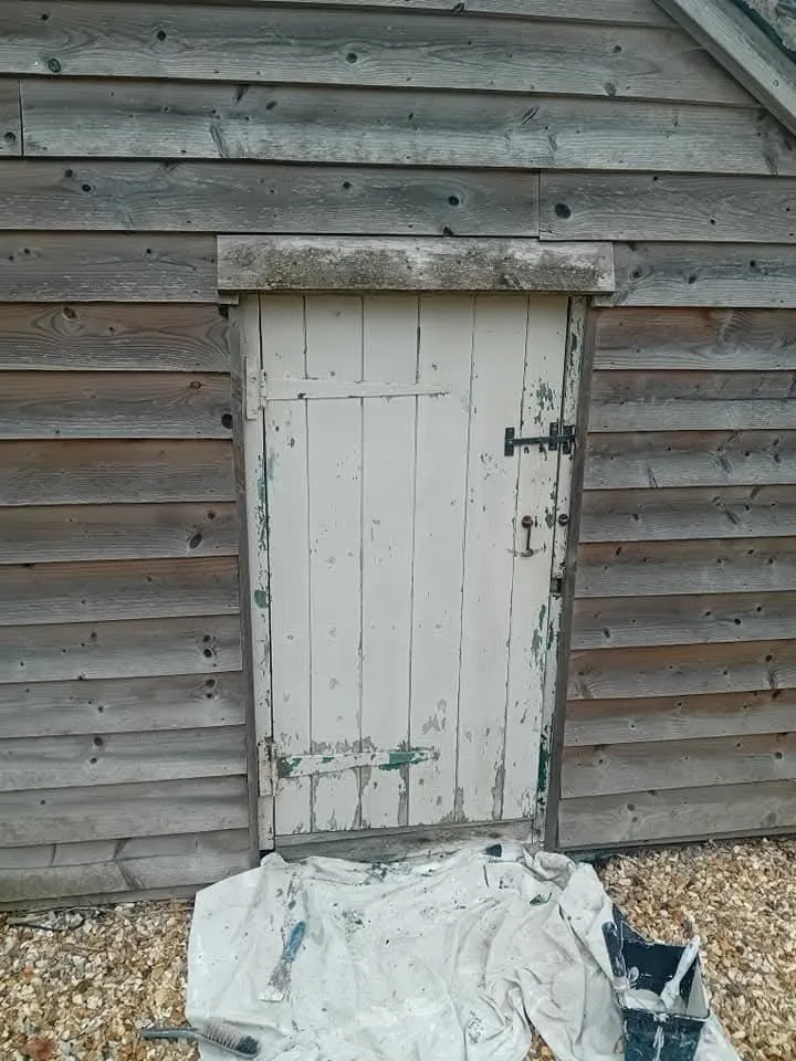A white door sitting next to a wooden building.