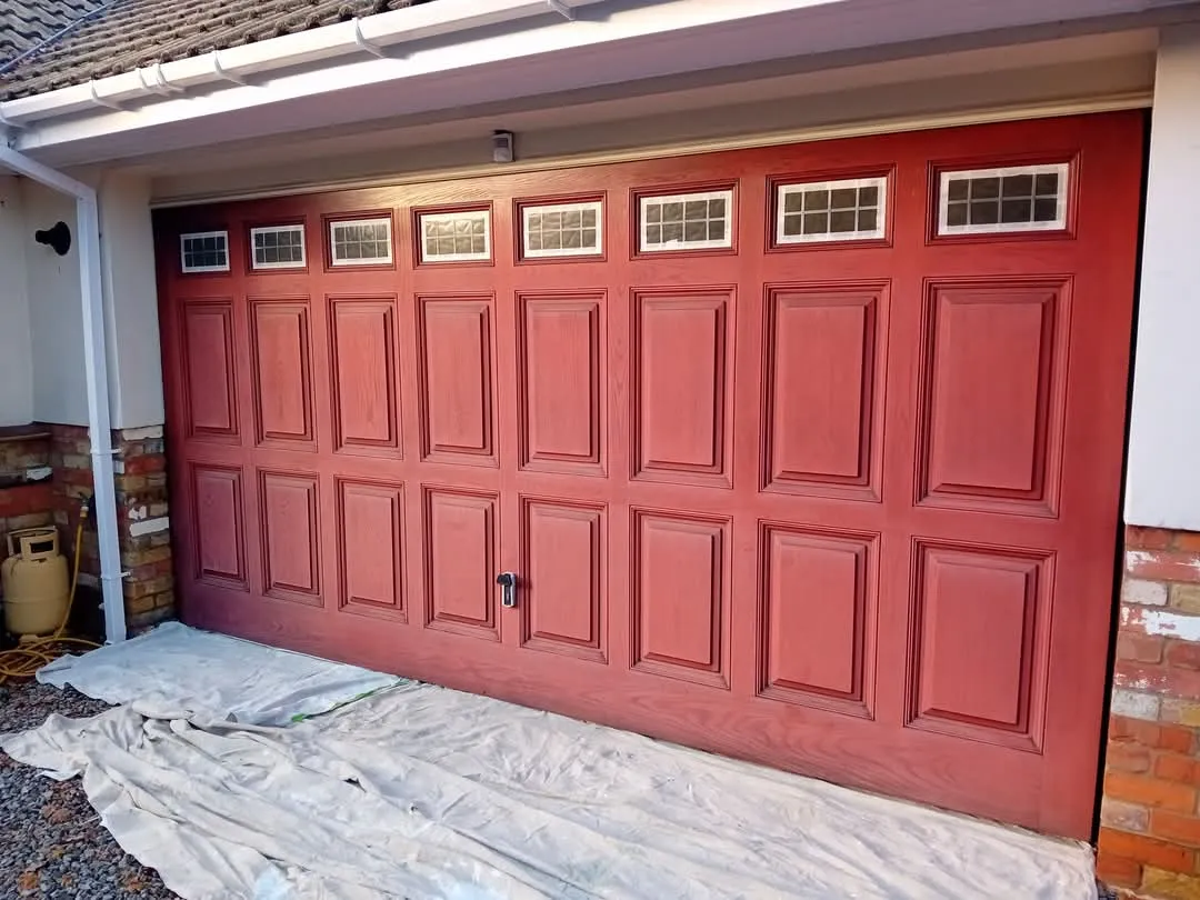 A red garage door is being painted red.