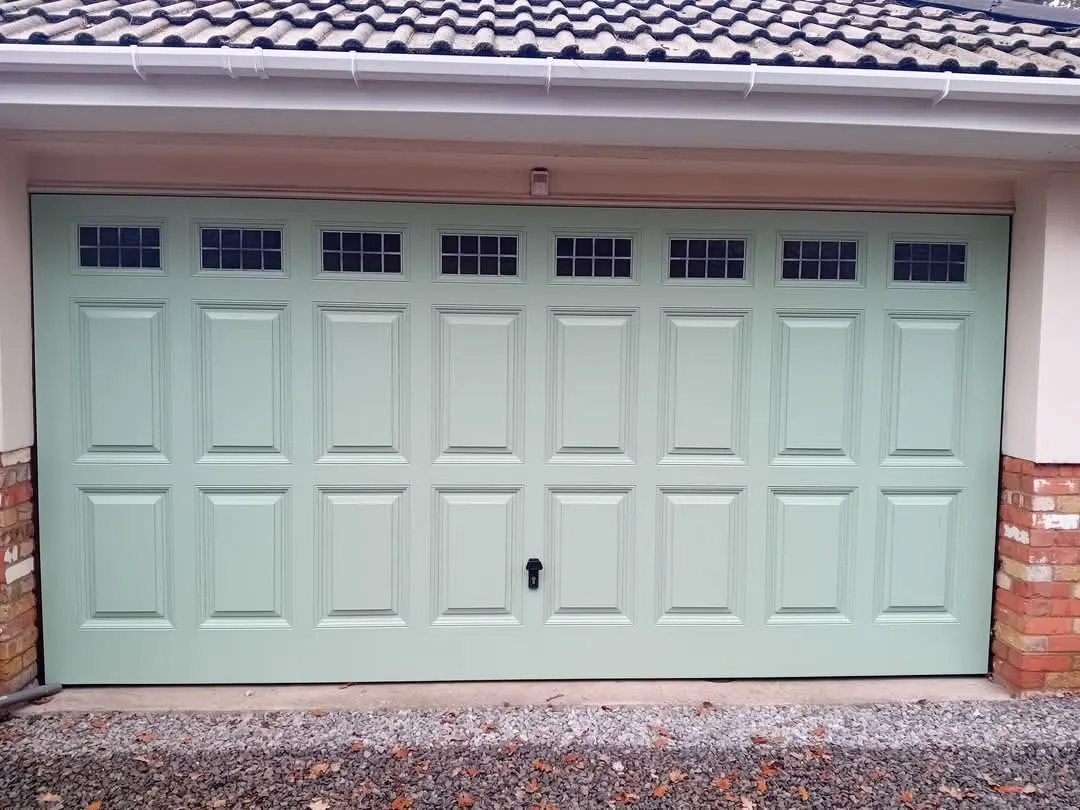 A green garage door in front of a brick building.