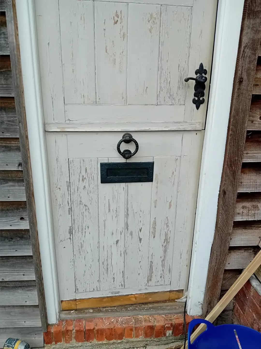 A white door with a blue trash can in front of it.