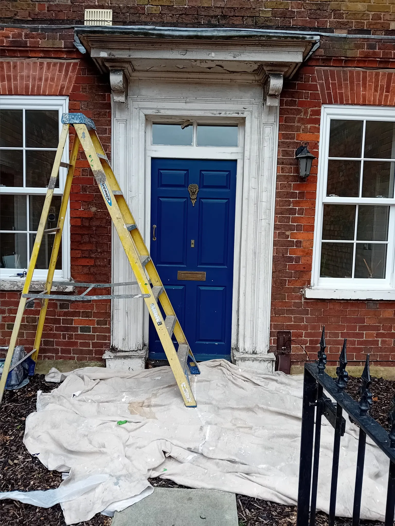 A house with a blue door and a yellow ladder.