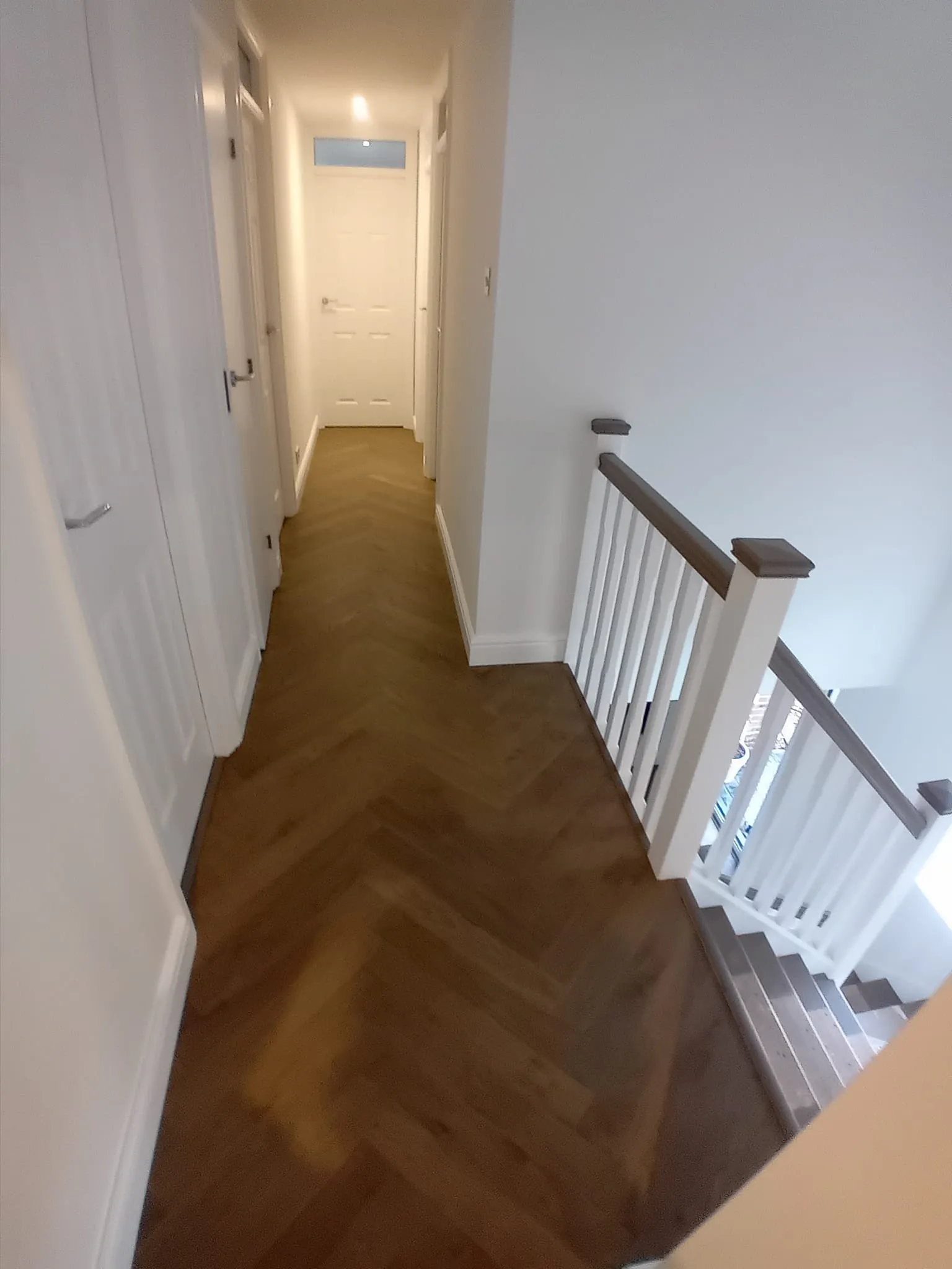 a long hallway with a wooden floor and white walls