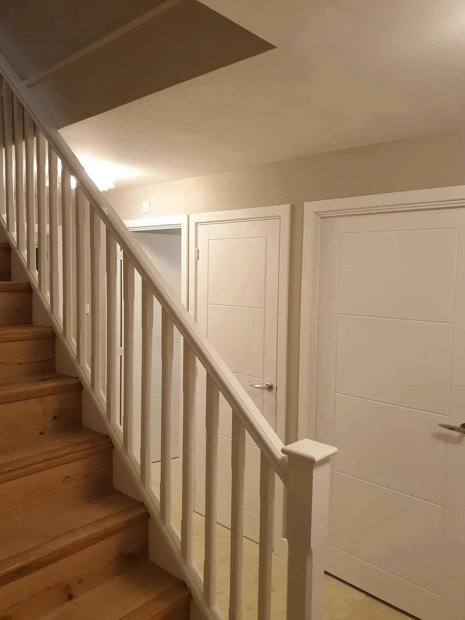 a white stair with wooden floors and white doors